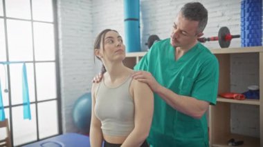 İyi donanımlı bir fizyoterapi kliniğinde bir kadını tedavi eden bir erkek..