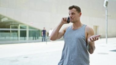 Şehir çevresindeki modern binalarla akıllı telefondan konuşan yakışıklı dövmeli adam.