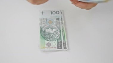 Ofis ortamında para sayan biri, ellere ve zloti faturalarına odaklanır.