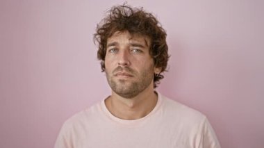 Yakışıklı, genç, İspanyol bir adam pembe arka planda poz veriyor, kameraya bakıyor..