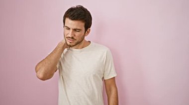 Sakallı genç bir İspanyol, pembe duvar arkasında boyun ağrısını hisseder..