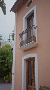 Tahta kapılı, balkonlu, banklı, bitkilerli ve bahçeli şık bir terra-cotta evi.