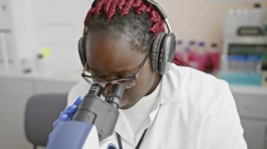 Laboratuvar ortamında mikroskop kullanan odaklanmış bir kadın bilim adamı sağlık araştırmalarını gösteriyor..