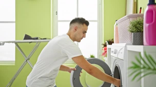 一个年轻人在室内洗衣服 用洗衣机在一间色彩艳丽的房间里描绘家庭生活 — 图库视频影像