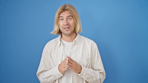 Erwachsener Mann Mit Blonden Haaren Gestikuliert Verwirrt Vor Einheitlichem Blauen — Stockvideo
