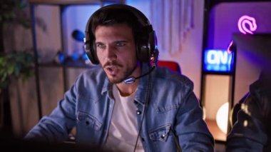 Gece karanlik bir odada kulaklik takan, neon isiklariyla aydınlatilan, stres ve konsantrasyonunu ifade eden Latin kökenli bir adam..