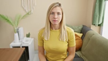 Evde utangaç sarışın bir kadın vardı. Gözlerini kapatıyordu ve el kol hareketi yapıyordu. Tişört giymek, korku ve negatif ifade sergilemek..