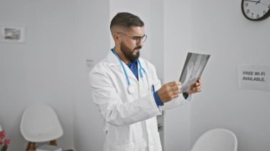 Beyaz önlüklü düşünceli bir adam modern bir klinikte uzmanlık ve sağlık hizmetleri profesyonelliği sunan bir röntgeni inceliyor..