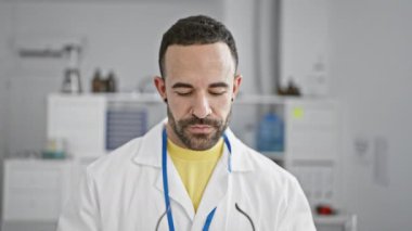 Sakallı, güvenlik gözlüklü, beyaz önlüklü, temiz bir laboratuvarda gülümseyen kendine güvenen bir İspanyol.