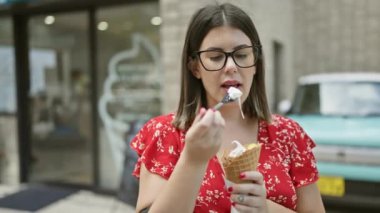 Neşeli, güzel, bardaklı İspanyol bir kadın Tokyo 'nun canlı caddesinde lezzetli bir dondurmanın tadını çıkarıyor. Şehrin şehir mimarisini kucaklıyor. Eğlence dolu yaz tatili gezisi boyunca.