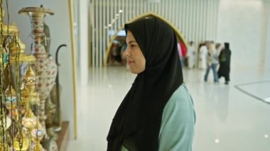 Türbanlı gülümseyen bir kadın, aydınlık bir camide, İslami kültür ve mimariyi sembolize eden süslü fenerlere hayran..