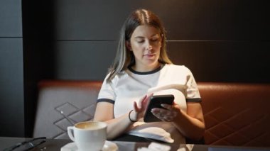 Bir kafede akıllı telefon kullanan bir kadın, kahve, bardak, rahatlama, kapalı alan, yetişkin, esmer, düşünceli, sakin, teknoloji...
