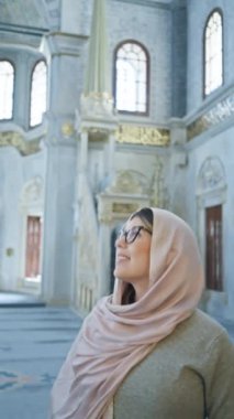 İstanbul 'da süslü bir caminin içinde tesettürlü gülümseyen kadın, İslami mimariyi gözler önüne seriyor..