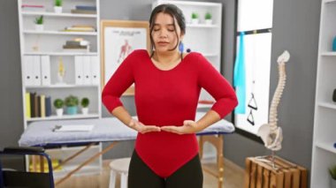 Genç bir İspanyol kadın, iyi donanımlı bir rehabilitasyon kliniğinin egzersiz odasında nefes egzersizleri yapıyor..