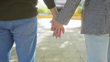 Erkek ve kadın el ele tutuşuyor, günlük kıyafetler giyiyor, geçmişi bulanık aşkı ve arkadaşlığı simgeliyor..