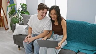 Irklar arası bir çift, bir erkek ve bir kadın, samimi bir oturma odasında dizüstü bilgisayar kullanırken, ev, teknoloji ve ilişkiyi sembolize ederken, birlikte sevgi dolu bir anı paylaşıyorlar..