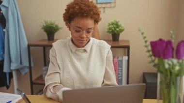 Neşeli Afro-Amerikalı kadın evinde oturmuş tamam işareti yapıyor, neşeli bir gülümsemeyle parmaklarından bakıyor.