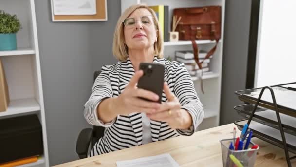 Smiling Mature Woman Taking Selfie Her Smartphone Modern Office Setting — Stock video