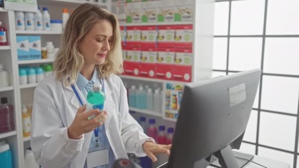 Uma Mulher Loira Farmacêutica Examina Produto Uma Farmácia Com Prateleiras — Vídeo de Stock