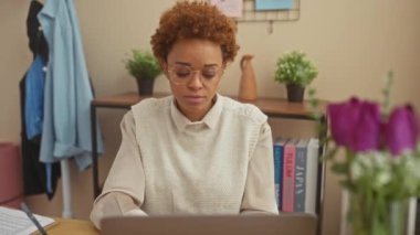 African american woman sitting on table showing middle finger, impolite and rude fuck off expression at home