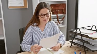 Modern ofis masasında çalışan neşeli bir kadın, başarıdan memnun.