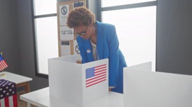 Afrika kökenli Amerikalı kadın seçimler sırasında bayraklarla içeride oy veriyor..