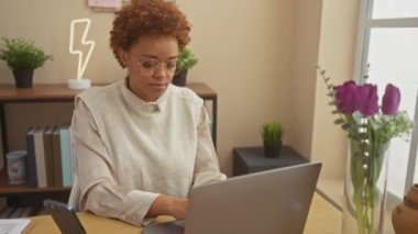Güzel afro-amerikalı kadın evinde, masada oturuyor, kulağını uzatıyor, neşeli bir şekilde dedikoduları dinliyor ve güzel bir sırıtışla dedikodu yapıyor, işitme kaybına rağmen.