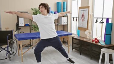Fizyoterapi kliniğinde egzersiz yapan genç İspanyol bir adam spor giysisi giymiş denge ve güç gösterisi yapıyor..