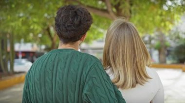 Açık havada sevgi dolu bir çift, ağaçlarla kaplı bir caddede bir kadını öpen bir adamla..