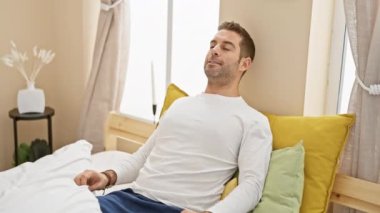 Rahat bir adam, dekoratif yastıklar ve doğal ışıkla rahat bir yatak odasında uzanıyor..