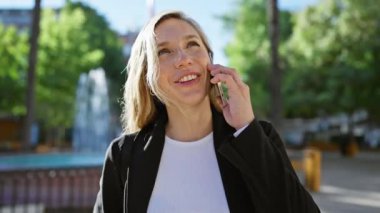 Sunny Park 'ta akıllı telefondan konuşan gülümseyen kadın.