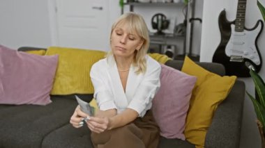 Beyaz kadın modern bir oturma odasında Şili pesolarını inceliyor.