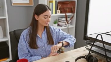 Genç ve güzel İspanyol kadın mutlu ve pozitif gülümsüyor, başparmak yukarı, ofiste mükemmel ve onay işareti yapıyor.