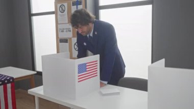 Takım elbiseli genç bir İspanyol Amerika Birleşik Devletleri oy kullanma merkezinde Amerikan bayraklarıyla oy kullanıyor.