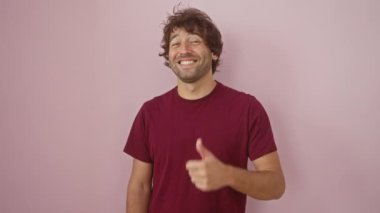 Neşeli, genç İspanyol bir adam. Parlak bir gülümsemesi ve havalı bir elbisesi var. İzole edilmiş pembe bir duvarın önünde duruyor.
