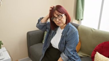 Tişörtlü belirsiz orta yaşlı İspanyol kadın ev sorusundan şüphe ediyor. Düşünceli iç mekan ifadesi dalgın bir konsept ortaya çıkarıyor.