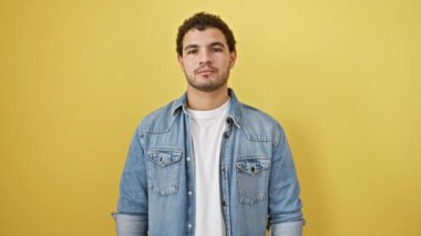 Düşünceli genç Arap bir adam, ifadesinde ayık, sarı izole edilmiş arka plana karşı pasaportunu elinde tutuyor, güven ve kararlılık yayıyor.