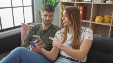 Bir kadın ve bir erkek, rahat ve modern bir oturma odasında, bir kanepede akıllı bir telefonla nişanlanırlar.