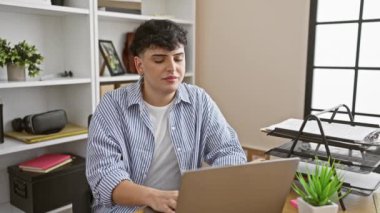 Modern ofis ortamında akıllı telefon ve dizüstü bilgisayar kullanan neşeli bir genç..