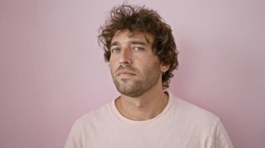 Genç İspanyol bir adam sade pembe bir arka plana karşı poz veriyor, sakin bir portre çiziyor..