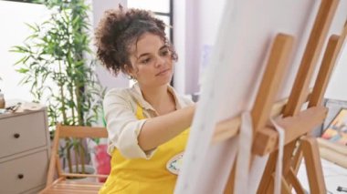 Kıvırcık saçlı İspanyol bir sanatçı kameraya öpücük yolluyor. Stüdyosunda seksi ve güzel görünüyor.