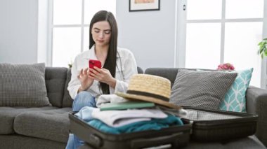 İspanyol kadın evde bavul hazırlarken telefon kullanıyor. Seyahate hazırlanıyor..