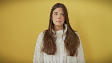 Şaşırtıcı bir keşif! Süveter giymiş genç, güzel İspanyol bir kadın, parmaklarını yana doğru uzatıyor, ağzı açık sarı duvar karşısında şaşkınlıkla bakıyor..