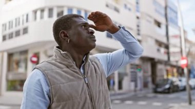 Sıradan giyinmiş Afrikalı bir adam dikkatle şehir caddesinde dikilirken...