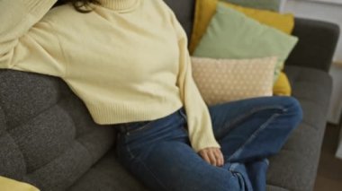 Özgüvenli gülümseme, gözlüklü güzel İspanyol kadın doğal olarak evde poz veriyor, yan bakıyor.