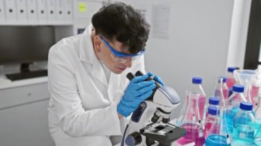 Genç bir bilim adamı, araştırma ve geliştirmeyi sembolize eden modern bir laboratuvarda mikroskop kullanırken gülümsüyor..