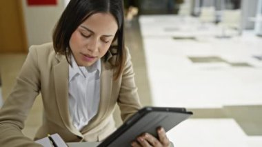 Profesyonel bir İspanyol kadın modern bir ofiste tabletine odaklanır.