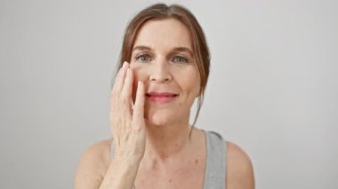 Beyaz arka planda kısa saçlı, gülümseyen orta yaşlı bir kadının portresi, nazikçe yüzüne dokunuyor..