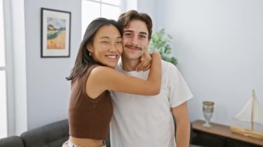 Modern bir oturma odasında kucaklaşan mutlu bir ırklar arası çift, bir yuva ortamında sevgi ve beraberlik sergiliyor..