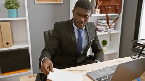 Сосредоточенный Черный Человек Читает Документы Современном Офисе Изображая Профессионализм Концентрацию — стоковое видео
